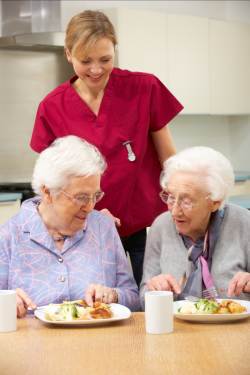 nurse assisting elder women to eat